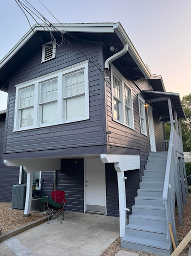 A blue house with white windows and stairs