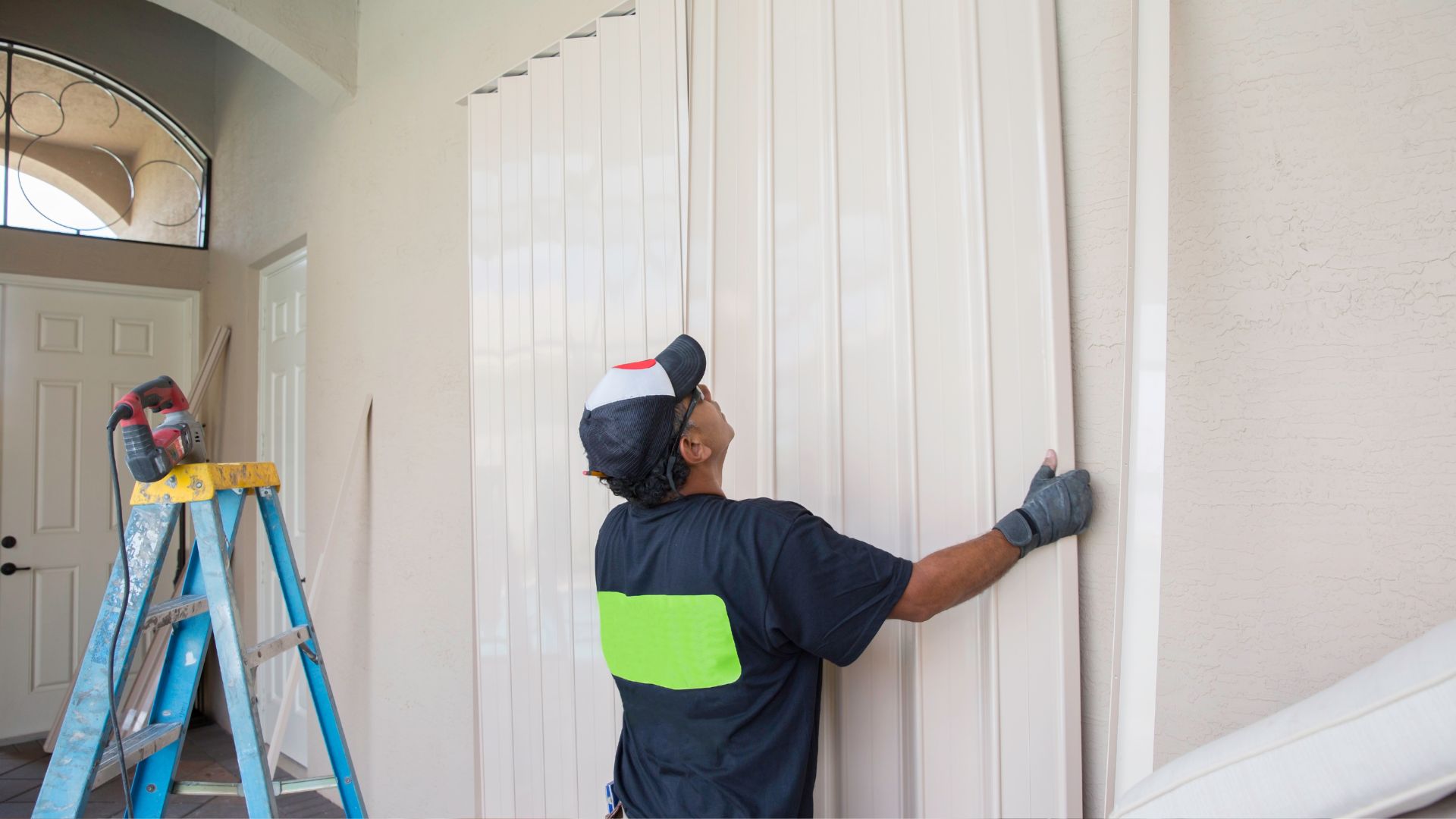 A man in a blue shirt is painting a wall