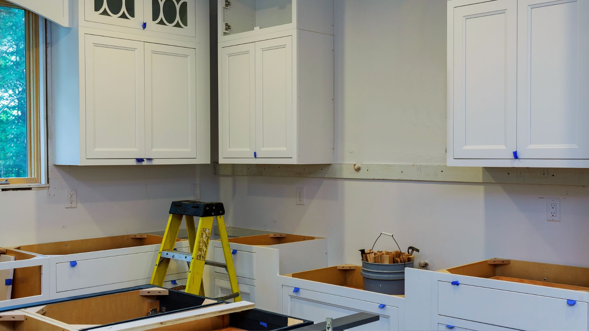 A kitchen with white cabinets and a yellow ladder