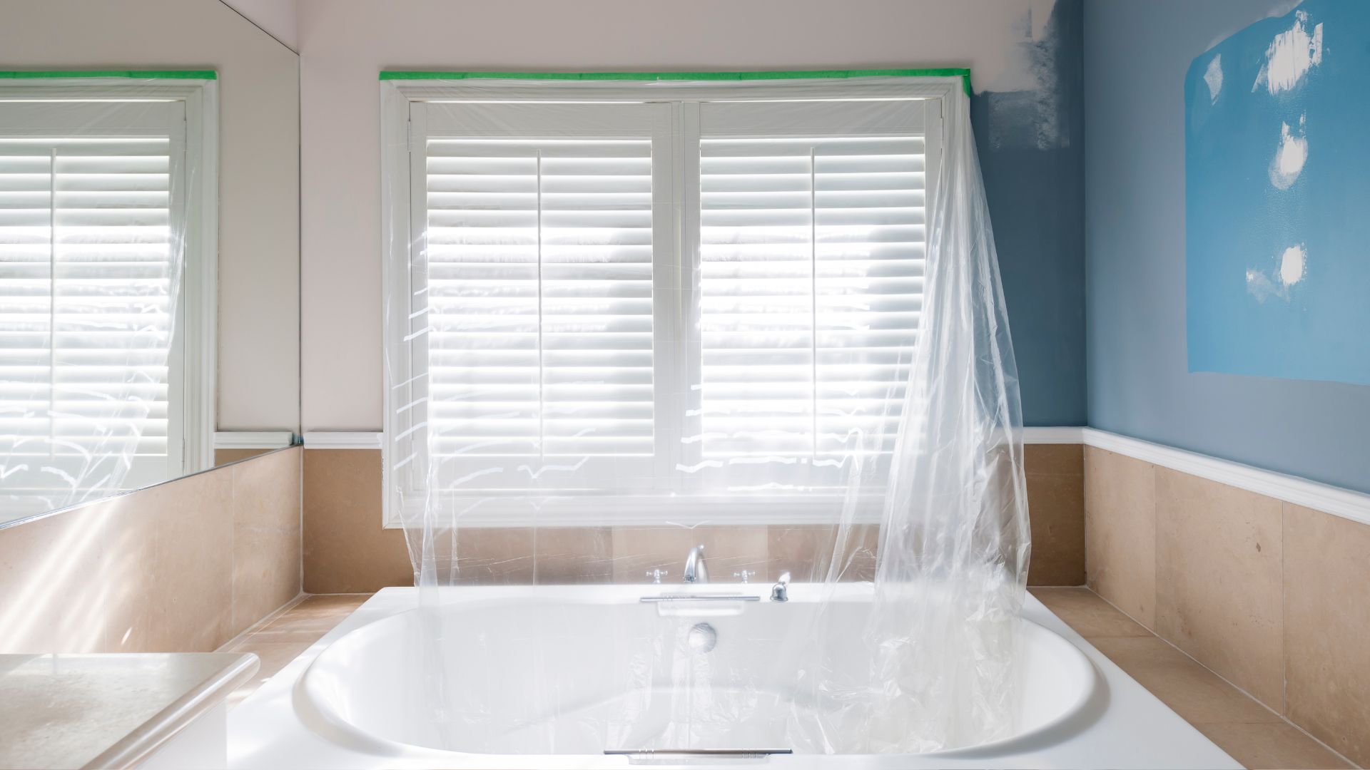 A white tub sitting under a window in a bathroom