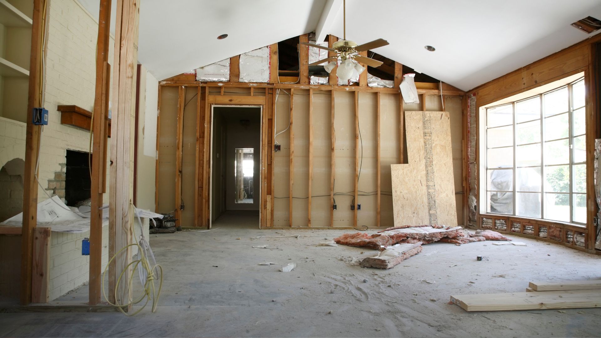 An unfinished room with a ceiling fan and windows